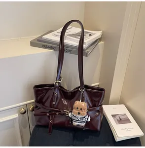 Détail du sac cabas en cuir ciré bordeaux avec un charmant accessoire de chiot en peluche