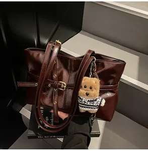 Détail du sac cabas en cuir ciré marron foncé avec boucle dorée et breloque chiot mignonne