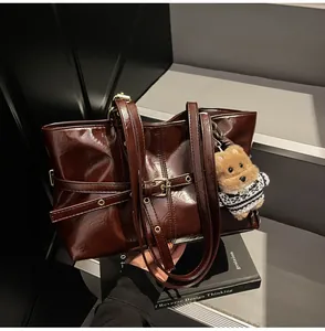 Détail d'un sac cabas en cuir ciré marron foncé avec finition brillante et bijou de sac