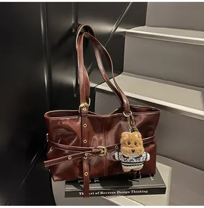 Détail d'un sac cabas en cuir ciré vintage avec lanières décoratives et breloque ours