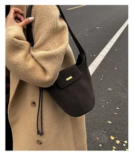 Gros plan du sac seau marron mat vintage avec boucle dorée et bandoulière détaillée
