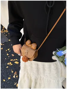 Dettaglio borsa a tracolla marrone da ragazza con fiocco 3D e ciondolo a pompon morbido