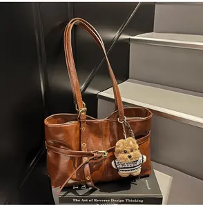 Détail du cabas vintage en cuir ciré marron avec un joli pendentif ours en peluche