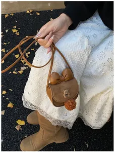 Vista dettagliata della mini borsa a tracolla marrone in camoscio con orso e fiocco