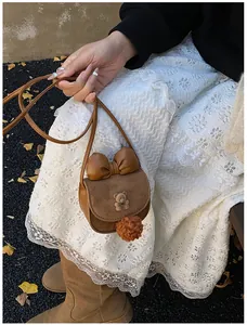 Dettaglio mini borsa a tracolla marrone da ragazza con orsetto di peluche e fiocco decorativo