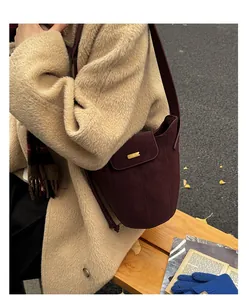 Détail du sac seau bordeaux en cuir givré avec boucle dorée et coutures verticales