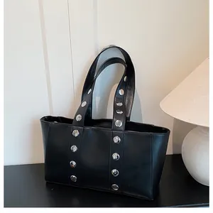 Detail of black leather tote bag featuring parallel silver metal rivets and chic punk style