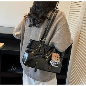 Détail du sac cabas en cuir ciré noir brillant avec pendentif ours et métal doré