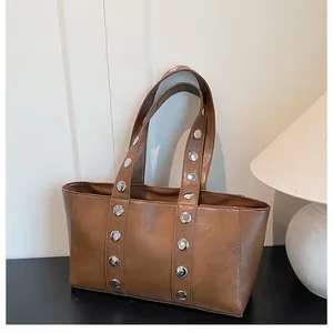Detailed view of brown leather bag featuring stylish silver rivets and smooth texture