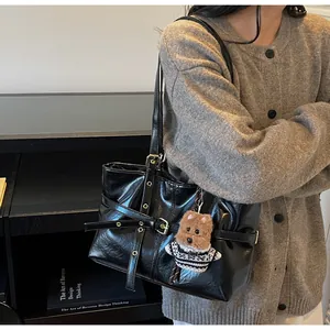 Détail du cabas en cuir noir brillant avec boucle métallique et pendentif ourson