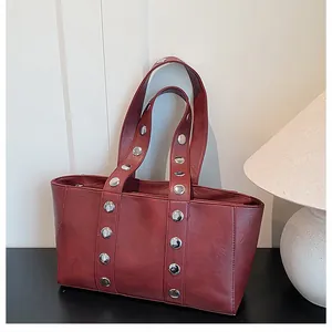 Close-up of dark red vintage leather tote bag with stylish silver metal rivets detail