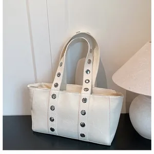 Detail of silver rivets on cream faux leather tote bag with soft textured finish