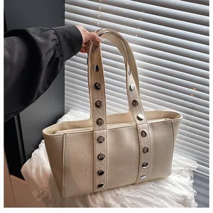 Detail of off-white tote bag with silver metal studs and premium leather texture