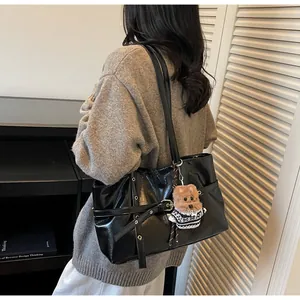 Détail du cabas en cuir ciré avec boucle en métal et breloque ours sur la bandoulière
