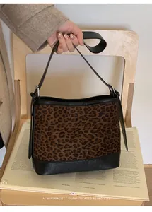 Detailed close-up of retro leopard print suede bucket bag with black leather straps