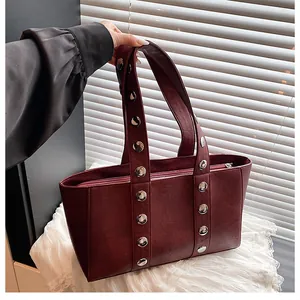 Detail of dark burgundy leather tote bag with silver rivets and zipper closure