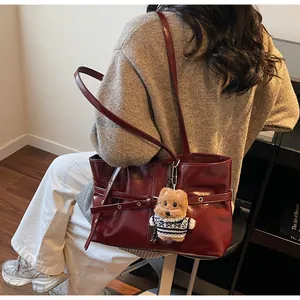 Détail d'un sac cabas en cuir ciré rouge avec un porte-clés en peluche ours très mignon