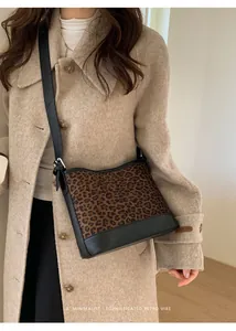 Detail of retro leopard print shoulder bag with adjustable black strap on a model