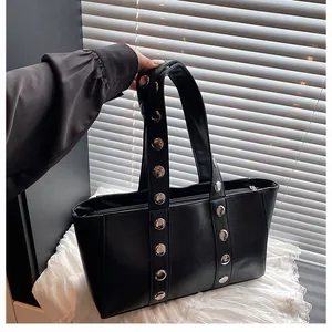 Detail of black PU leather shoulder bag featuring silver metal rivets and a zipper closure