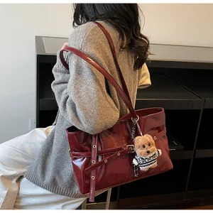 Détail du cabas en cuir ciré bordeaux avec œillets dorés et breloque en peluche