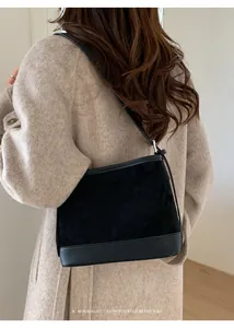 Detail of a black suede minimalist tote bag styled on a beige coat from a back perspective