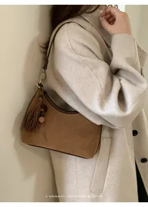 Brown suede underarm baguette bag with fringe tassel and wood beads on light coat