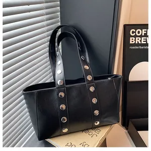 Close-up of black PU tote bag with silver studs on shoulder straps and sleek stitching