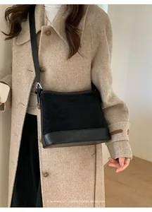 Minimalist black suede and leather tote bag styled with a beige coat for a retro vibe