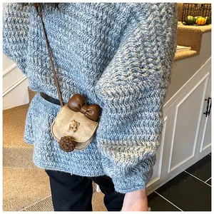 Dettaglio mini borsa a tracolla marrone in camoscio con orsetto di metallo e fiocco