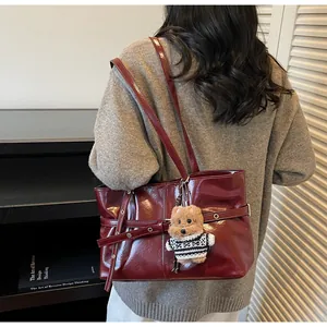 Détail du cabas en cuir ciré rouge foncé avec boucle décorative et breloque chiot en peluche