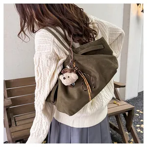 Detail of olive green suede tote bag featuring drawstring design and bear charm