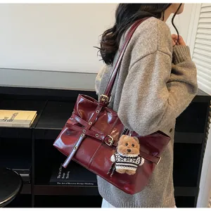 Détail du cabas en cuir ciré bordeaux avec boucles métalliques et breloque ourson