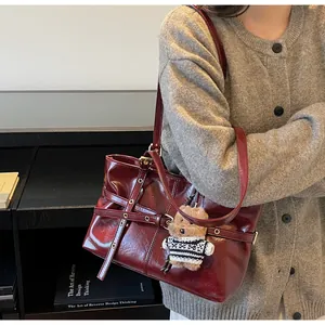 Détail du grand sac cabas en cuir bordeaux avec œillets métalliques et ourson