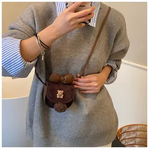 Dettaglio della mini borsa a tracolla marrone con orsetto 3D, fiocco e pompon di peluche