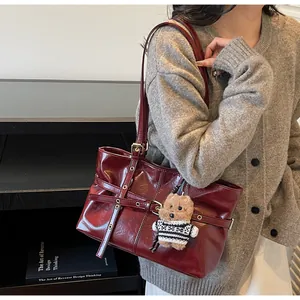 Détail du sac cabas en cuir bordeaux avec clous dorés et pendentif ours en peluche