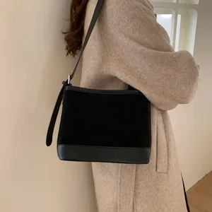 Vintage black suede tote bag with leather拼接, styled on model wearing a beige wool coat