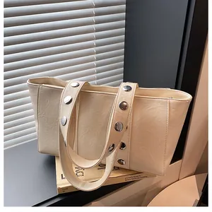 Detail shot of cream-white PU leather tote with large silver metallic rivets on the strap