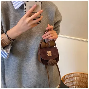 Dettaglio mini borsa a tracolla in pelle scamosciata con orsetto e fiocco marrone