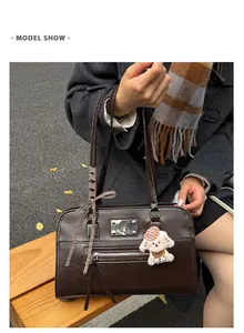 Close-up of vintage brown tote bag with zipper pocket, ribbon bow, and plush puppy charm
