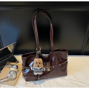 Détail du cabas en cuir ciré bordeaux avec pendentif peluche et accessoires de bureau
