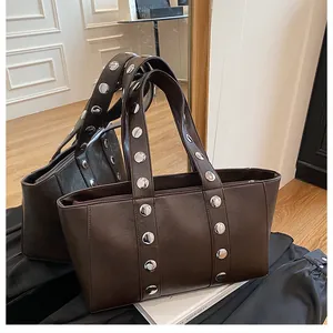 Detailed macro view of dark brown tote bag featuring oversized silver metallic rivets