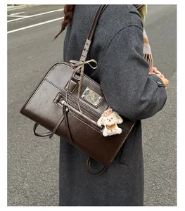 Close-up of vintage brown leather tote bag detail with metal plate and puppy charm