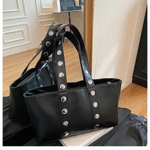 Detail of black faux leather tote featuring silver rivets on a structured shoulder strap