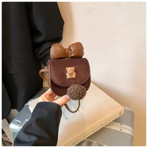 Dettaglio di una mini borsa a tracolla marrone in camoscio con fiocco e orsetto peluche