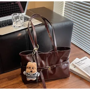 Détail du sac cabas en cuir ciré marron foncé avec un pendentif chien et boucle dorée