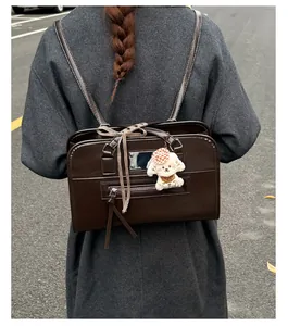 Detail of dark brown vintage tote bag with decorative bow and plush puppy charm accessory