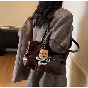 Détail du cabas en cuir ciré marron foncé brillant avec breloque ours et boucle métal