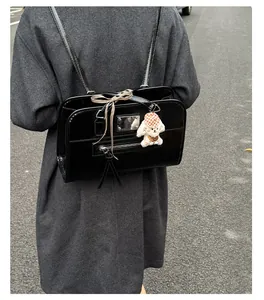 Detail of glossy black patent leather tote bag with silver hardware and cute puppy charm