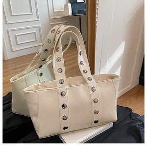 Detail of cream tote bag with large silver metal rivets and natural leather texture