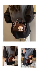 Detail of vintage brown glossy pillow bag with dog charm and ribbon decoration